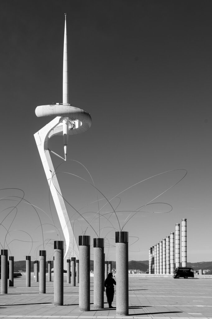 Montjuïc's communications tower rising above a row of concrete columns and looping wire sculptures