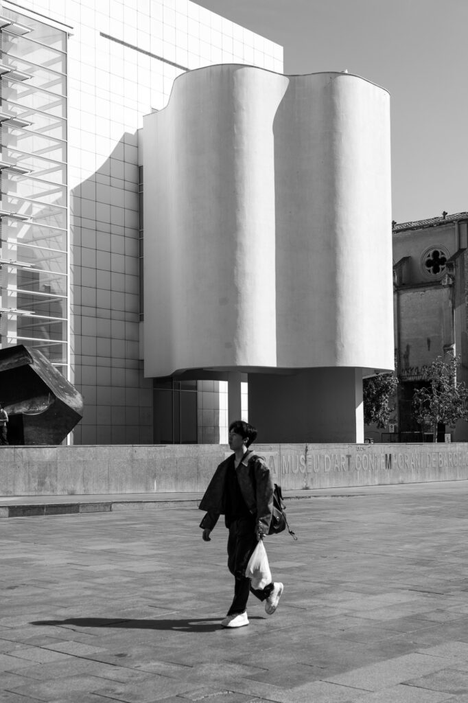 A man walking past MACBA's curved white sculptural wall in Barcelona