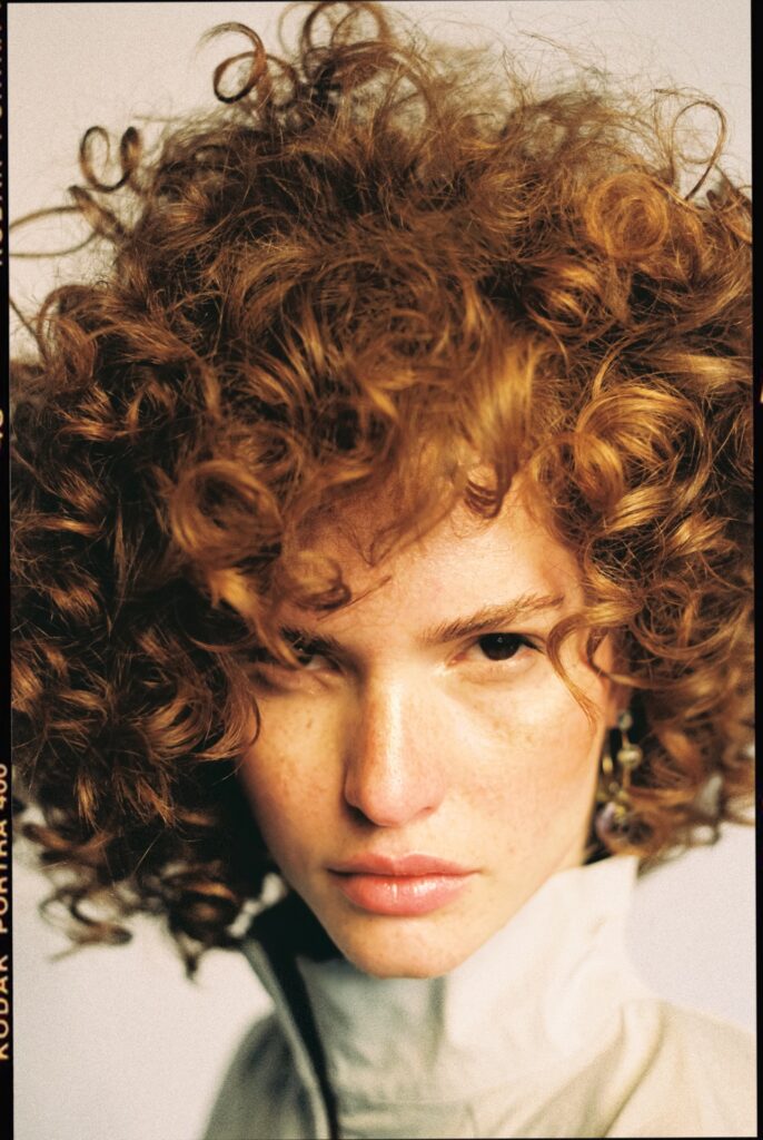 35mm colour negative frame, portrait of a model with curly red hair, film edge marking Kodak Portra 400 visible