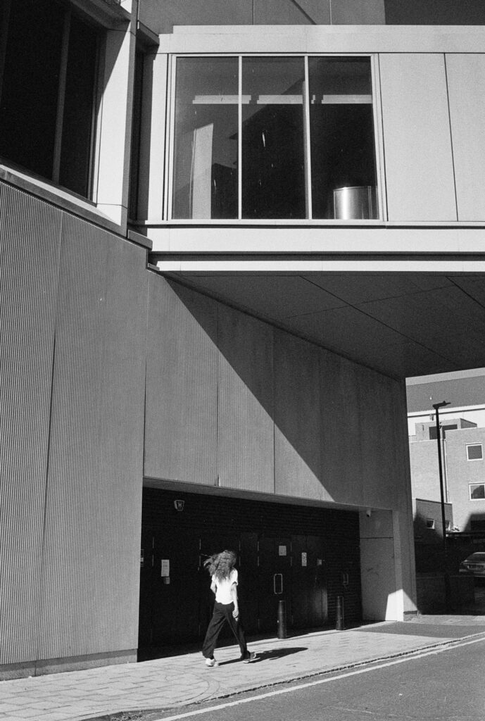A woman in white walks past a black doorway