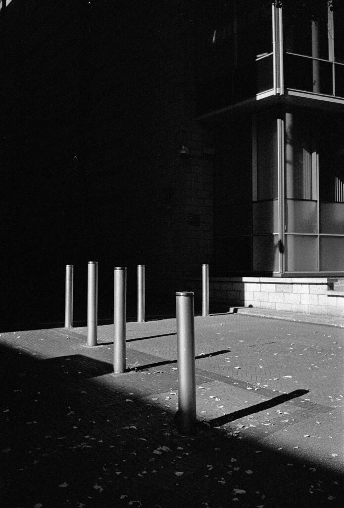 Metal bollards appear to cordon off a shadowed area