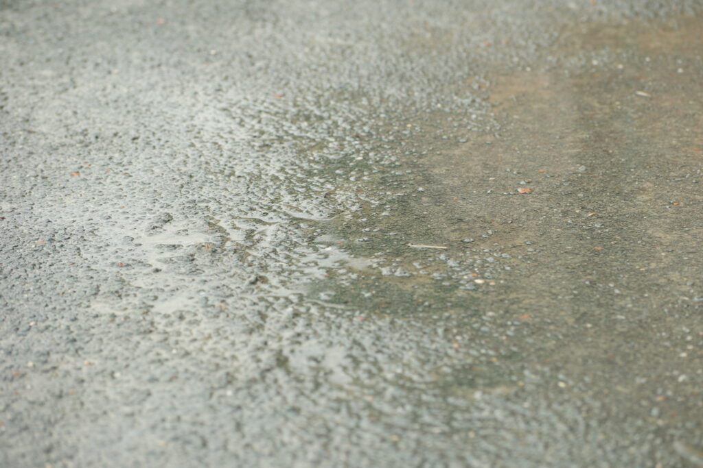 A photograph of a puddle on a footpath.