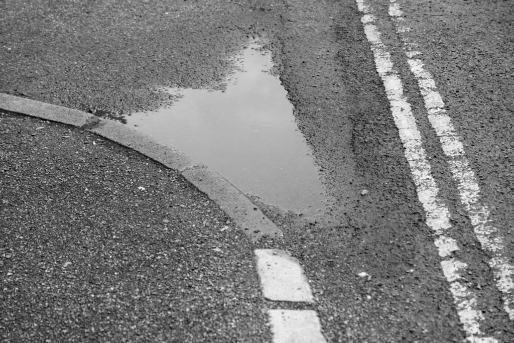 A monochrome image showing a puddle following heavy rain.