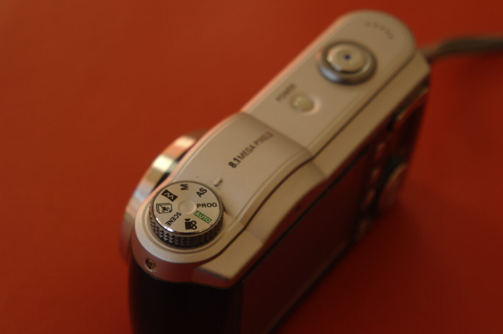 Colour image showing the top plate and mode dial of the Samsung Digimax L85 digital compact camera